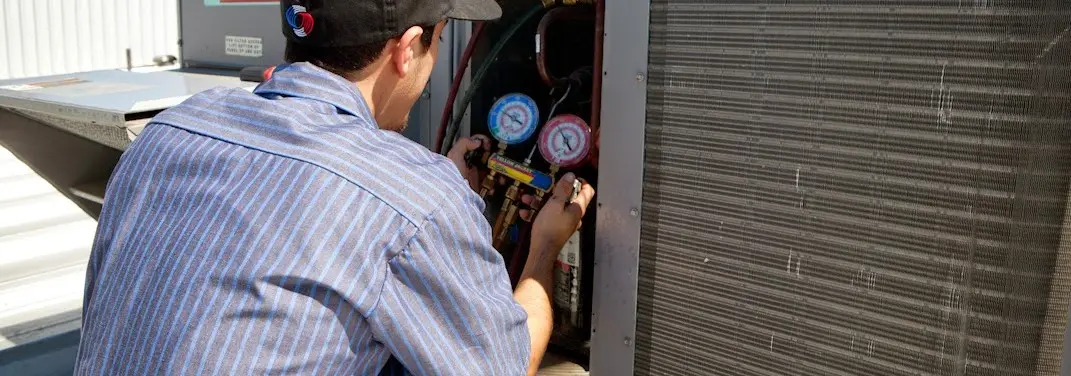 HVAC technician servicing a condenser unit in Arvada